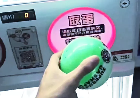 Step 3: The capsule drops into the retrieval slot; customers take it and open it to reveal their prize.